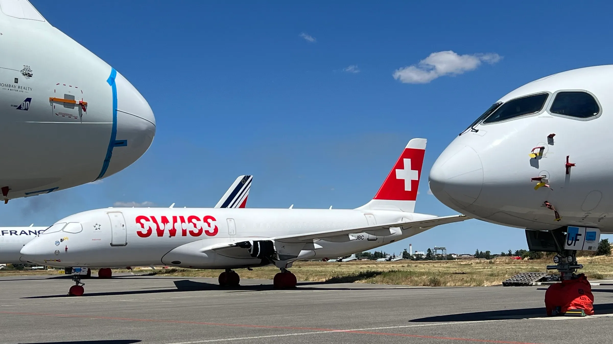 A SWISS Airbus A220 parked between engineless stored widebodies at Toulouse-Francazal