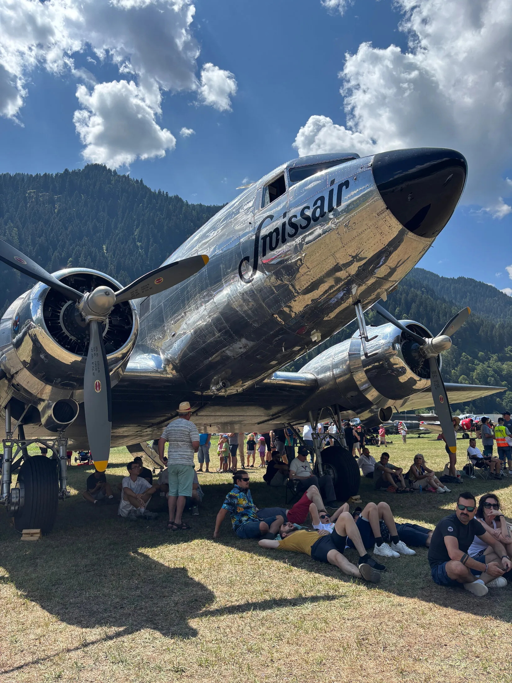 Polished Swissair DC-3 with a crowd sitting in its shade